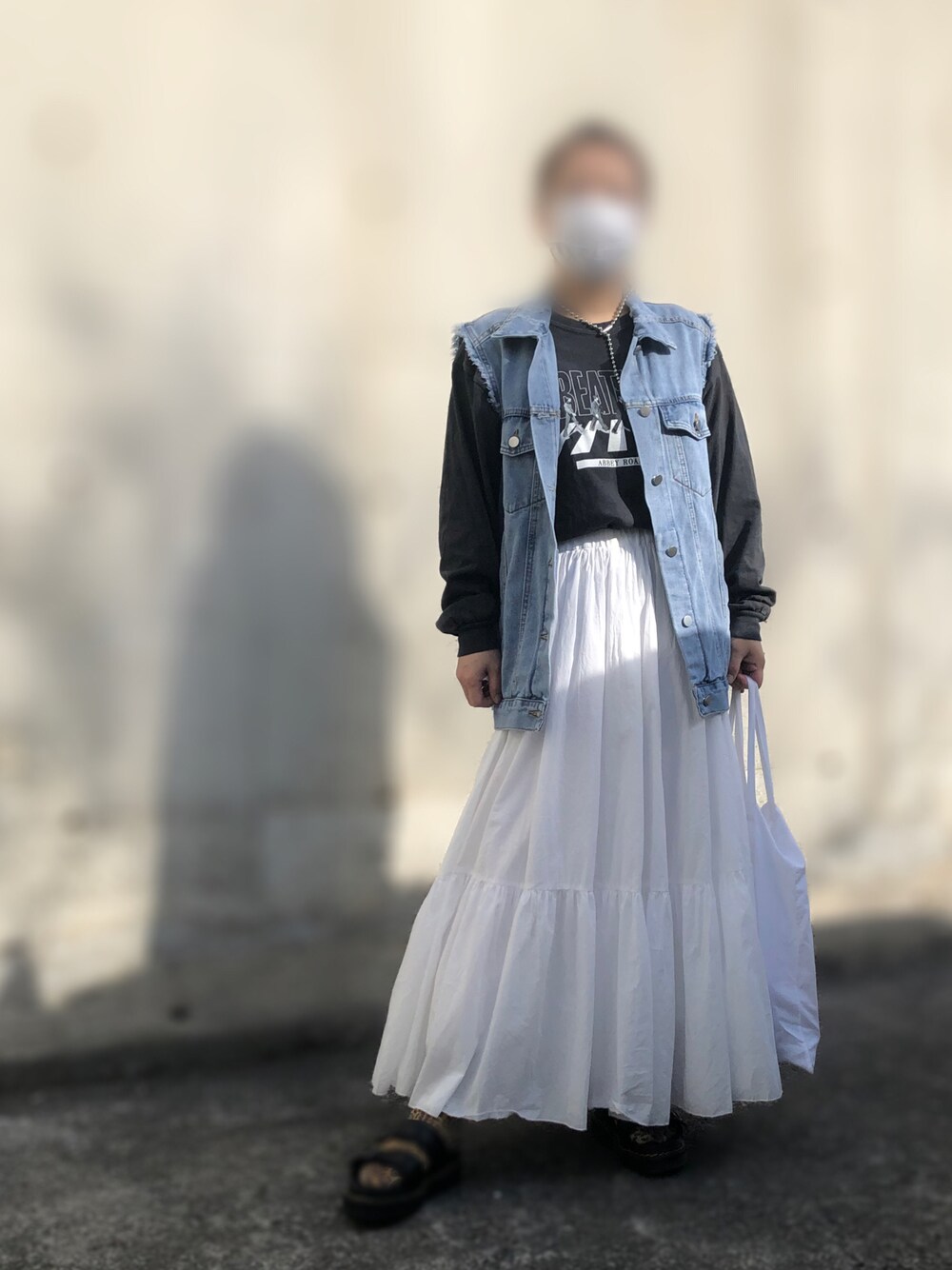 ブラック系のTシャツ/カットソー、ブルー系のベスト、ホワイト系のスカートを着用したレディースの春コーディネートの1枚目の写真