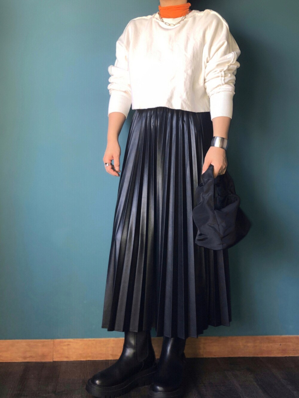 ブラック系のハンドバッグ、オレンジ系のTシャツ/カットソー、ブラック系のスカートを着用したレディースの秋コーディネートの1枚目の写真