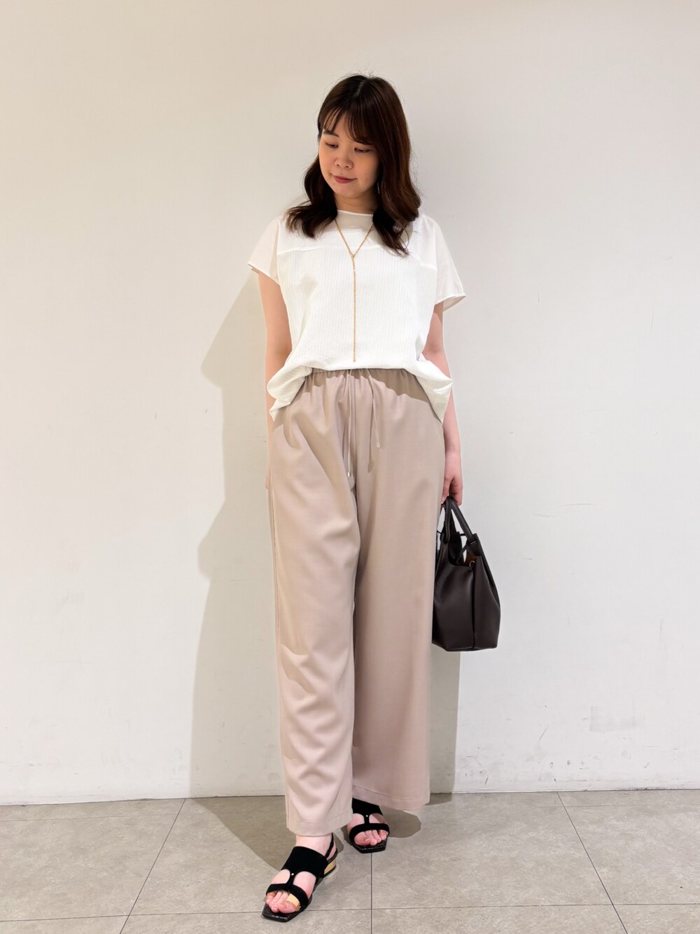 ホワイト系のTシャツ/カットソー、ベージュ系のその他パンツ、ブラック系のサンダルを着用したレディースの夏コーディネートの1枚目の写真