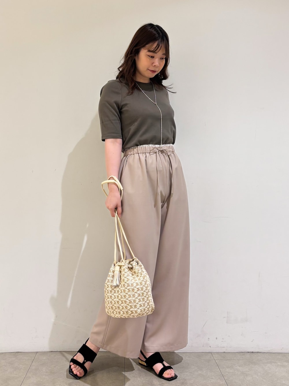 ベージュ系のその他パンツ、ホワイト系のショルダーバッグ、ブラック系のサンダルを着用したレディースの夏コーディネートの1枚目の写真