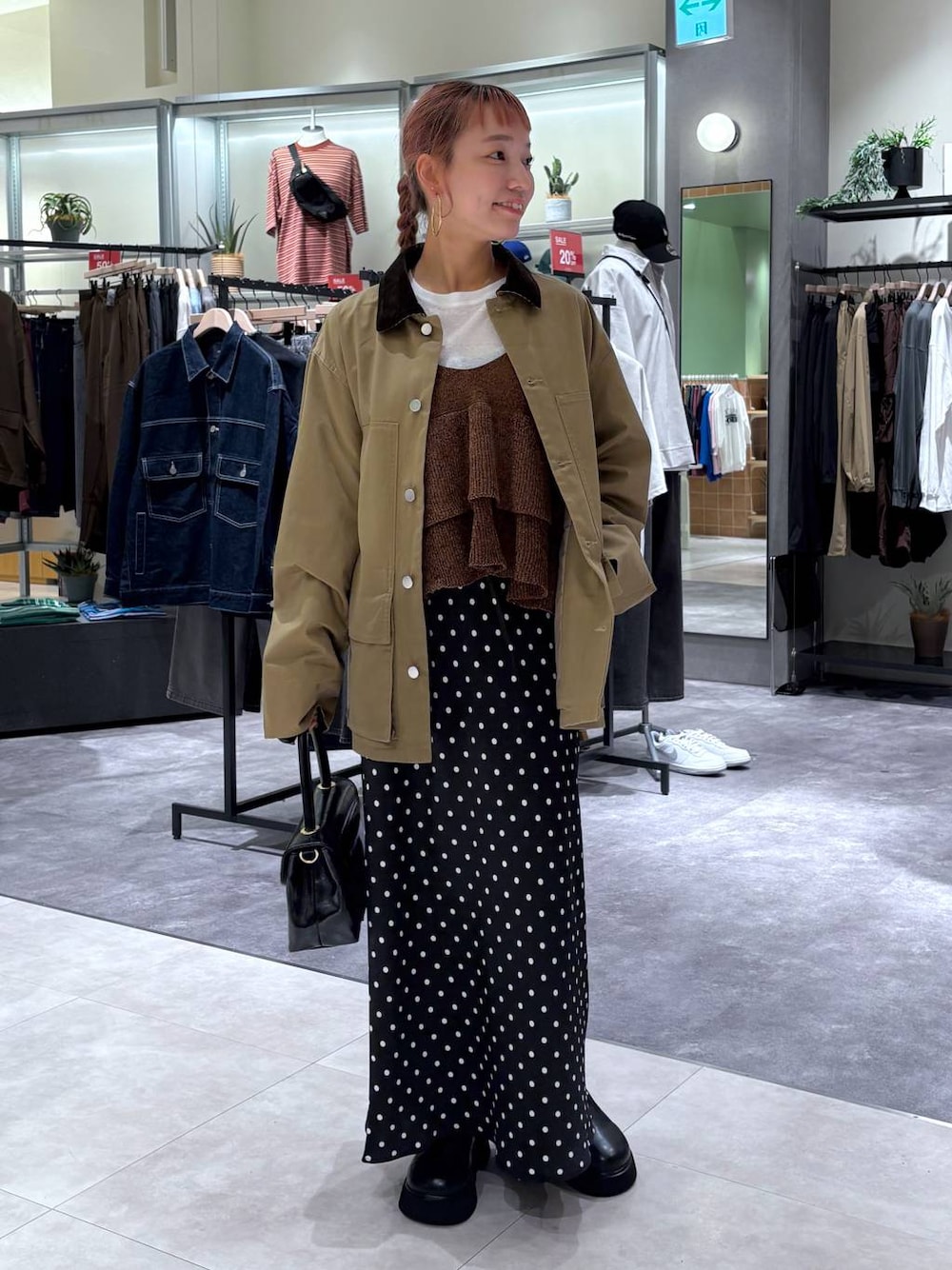 ブラック系のスカート、ブラウン系のブルゾン、ブラック系のボストンバッグを着用したレディースの秋コーディネートの1枚目の写真