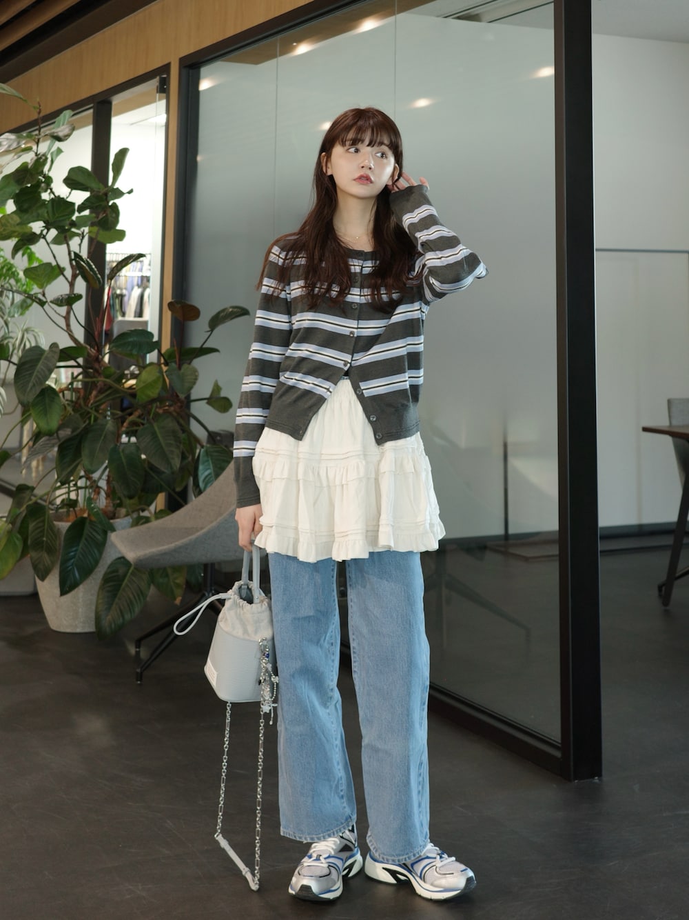 ブルー系のデニムパンツ、ホワイト系のスカート、シルバー系のスニーカーを着用したレディースの春コーディネートの1枚目の写真