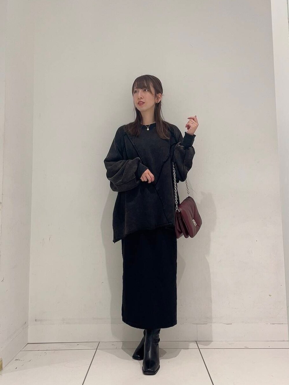 ブラック系のスカート、ブラック系のブーツ、レッド系のショルダーバッグを着用したレディースの秋コーディネートの1枚目の写真