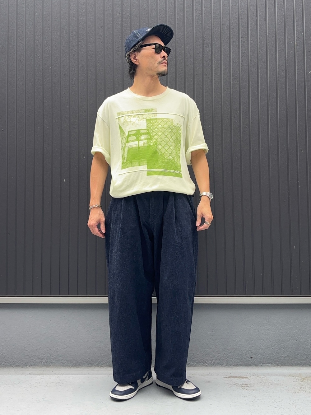 イエロー系のTシャツ/カットソー、ブルー系のデニムパンツ、グレー系のスニーカーを着用したメンズの秋コーディネートの1枚目の写真