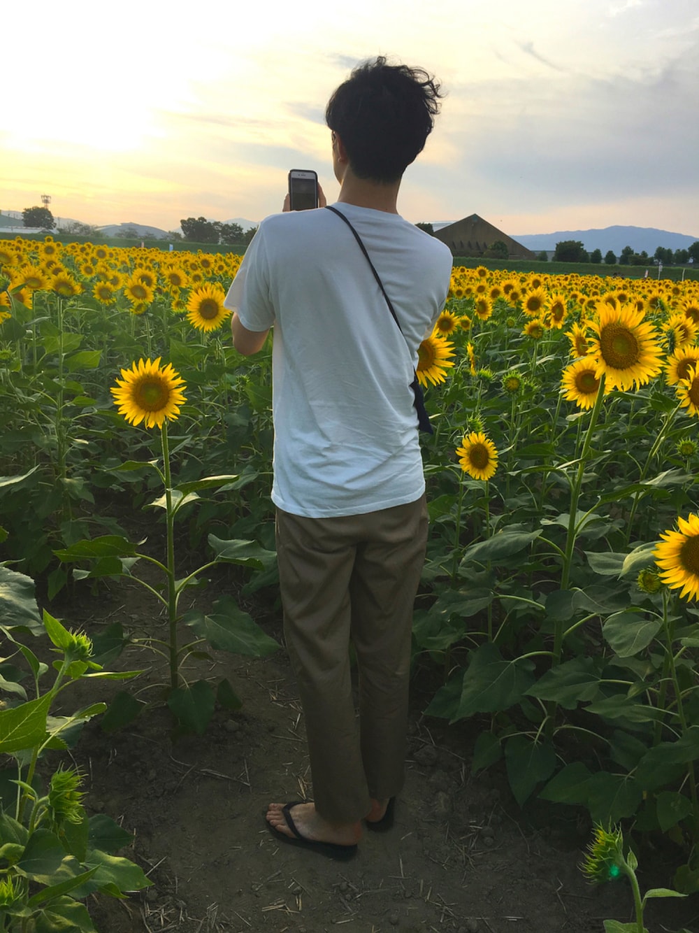 ベージュ系のチノパンツ、ブラック系のビーチサンダル、ホワイト系のTシャツ/カットソーを着用したメンズの夏コーディネートの1枚目の写真