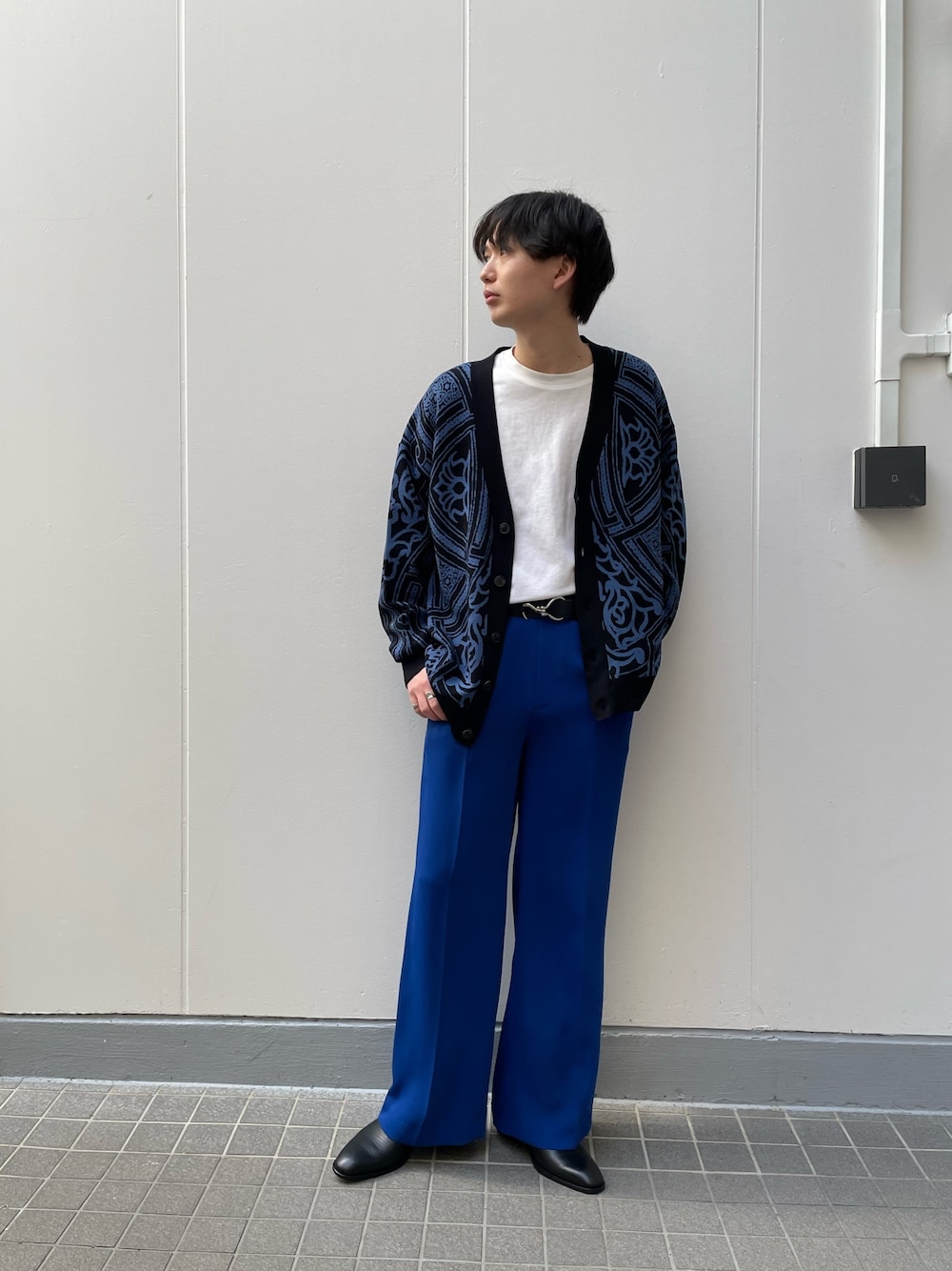 ブラック系のカーディガン/ボレロ、ブラック系のドレスシューズ、ブルー系のスラックスを着用したメンズの春コーディネートの2枚目の写真