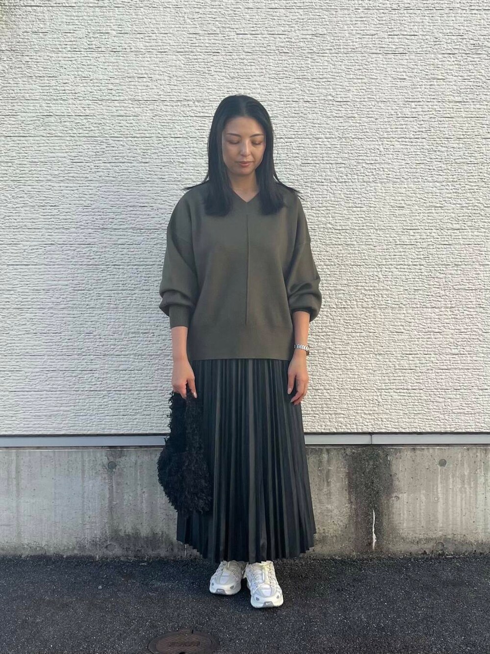 ブラック系のショルダーバッグ、グリーン系のニット/セーター、ホワイト系のスニーカーを着用したレディースの秋コーディネートの1枚目の写真