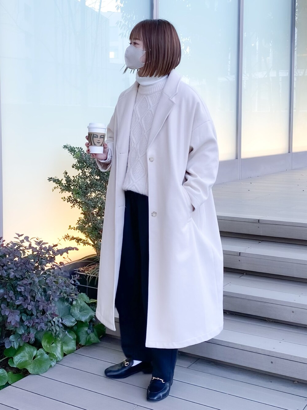 ホワイト系のチェスターコート、ホワイト系のニット/セーター、ホワイト系のTシャツ/カットソーを着用したレディースの冬コーディネートの1枚目の写真