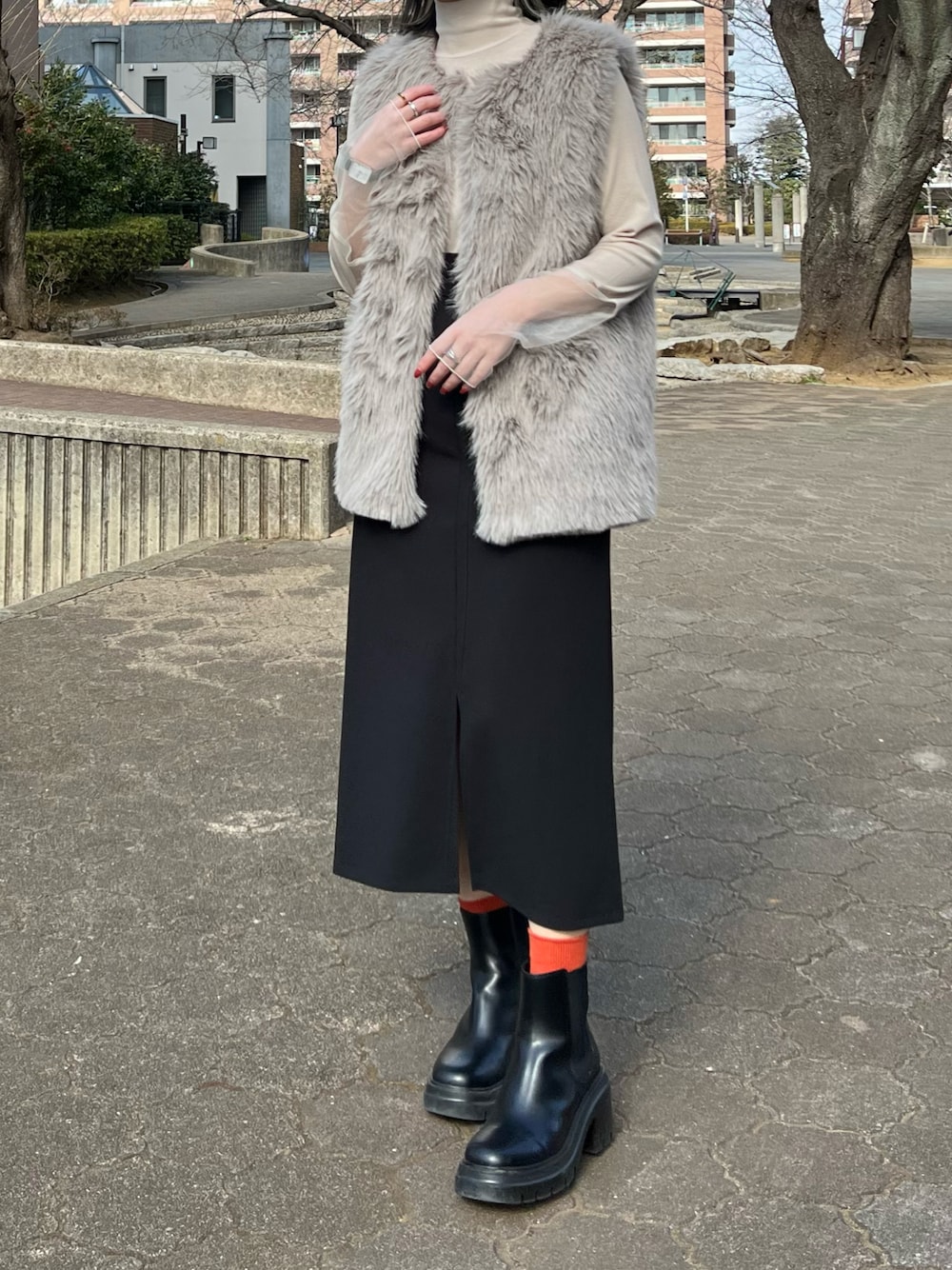 ベージュ系のTシャツ/カットソー、グレー系のベスト、ブラック系のジャンパースカートを着用したレディースの冬コーディネートの1枚目の写真