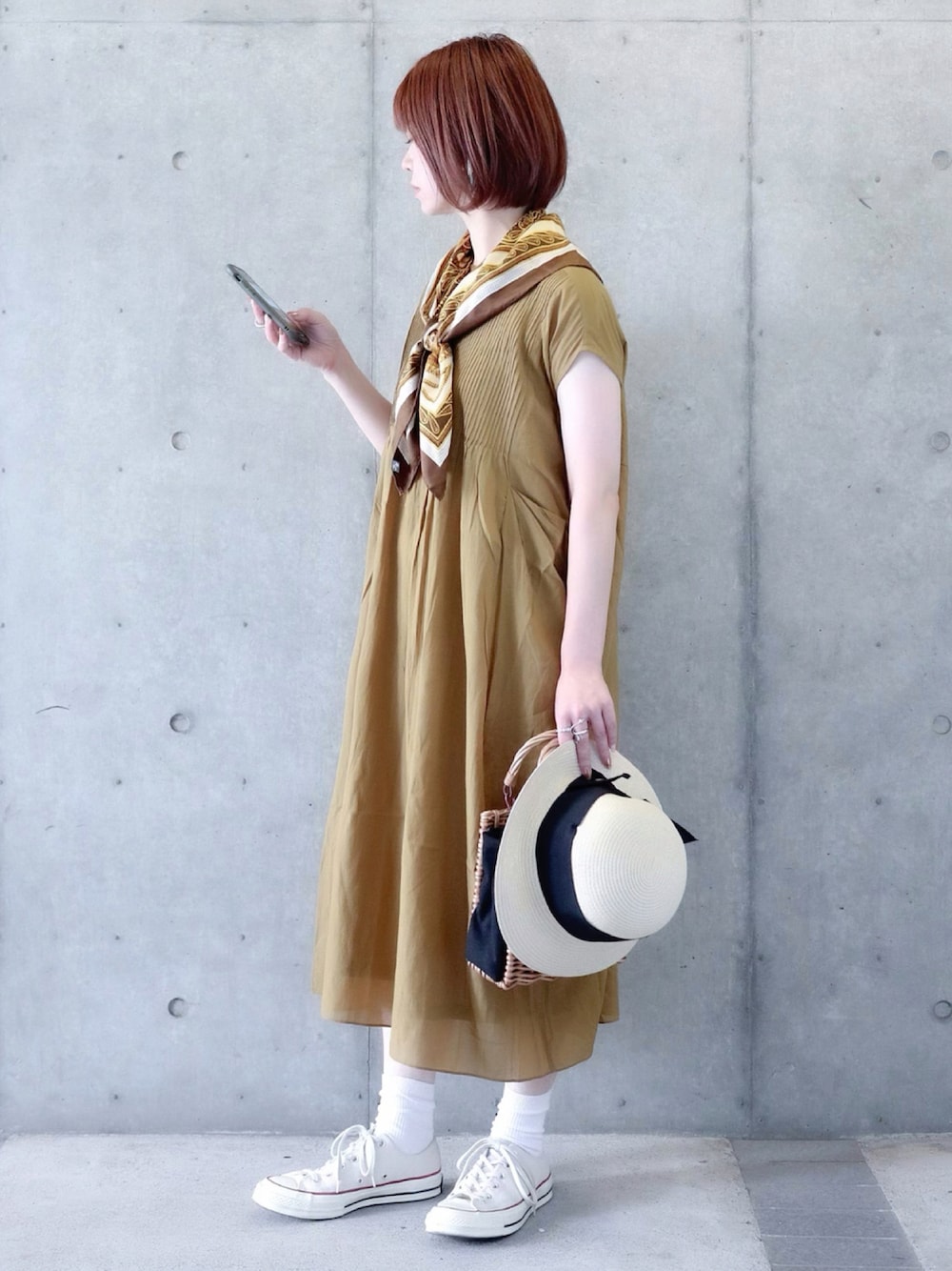 イエロー系のワンピース、ベージュ系のハンドバッグ、ホワイト系のスニーカーを着用したレディースの夏コーディネートの1枚目の写真