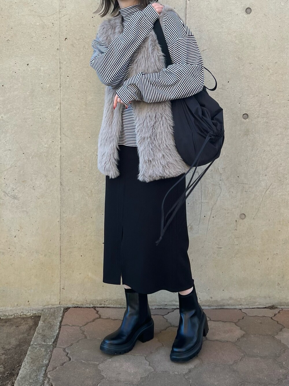 ブラック系のバッグ、ブラック系のジャンパースカート、ブラック系のブーツを着用したレディースの冬コーディネートの1枚目の写真