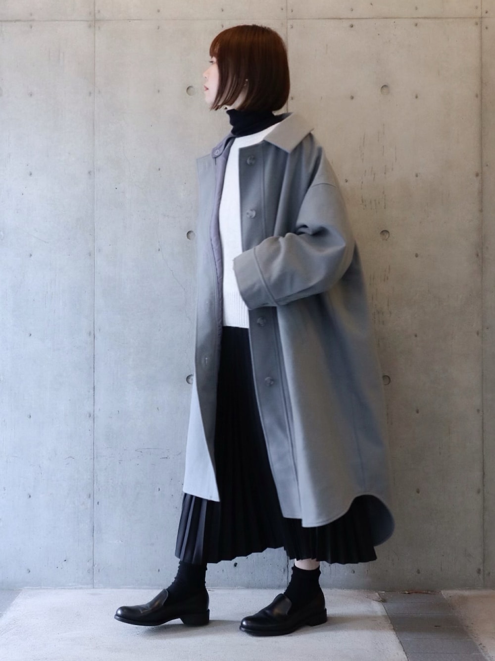 グレー系のダウンジャケット/コート、グレー系のニット/セーター、ブラック系のスカートを着用したレディースの冬コーディネートの1枚目の写真