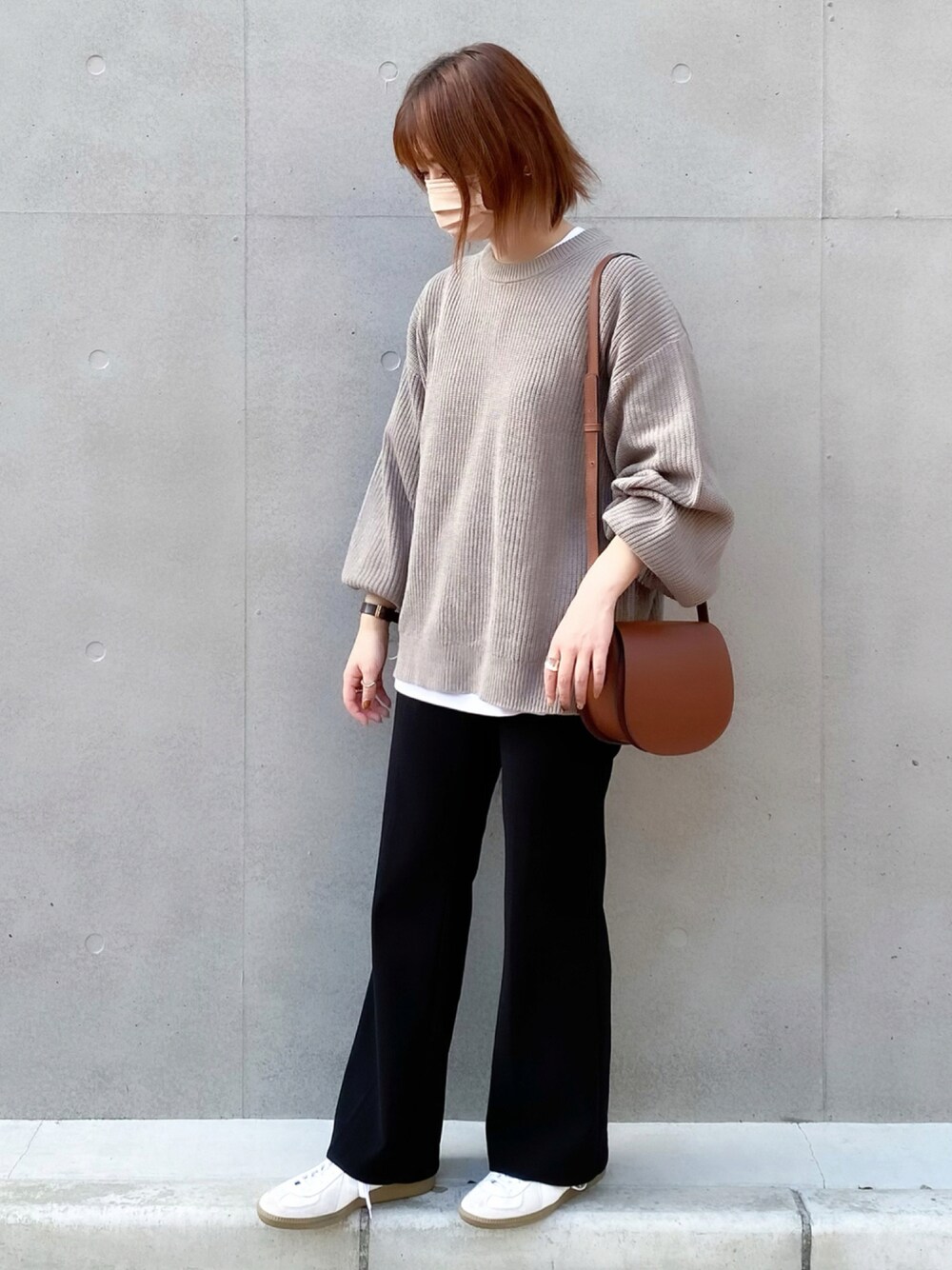 ベージュ系のニット/セーター、ブラウン系のバッグ、ホワイト系のスニーカーを着用したレディースの秋コーディネートの1枚目の写真