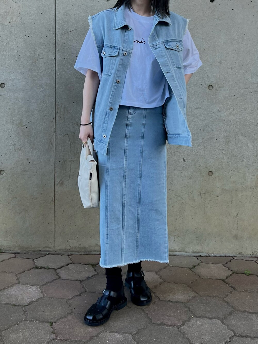 ブルー系のベスト、ブルー系のデニムスカート、ホワイト系のTシャツ/カットソーを着用したレディースの春コーディネートの1枚目の写真