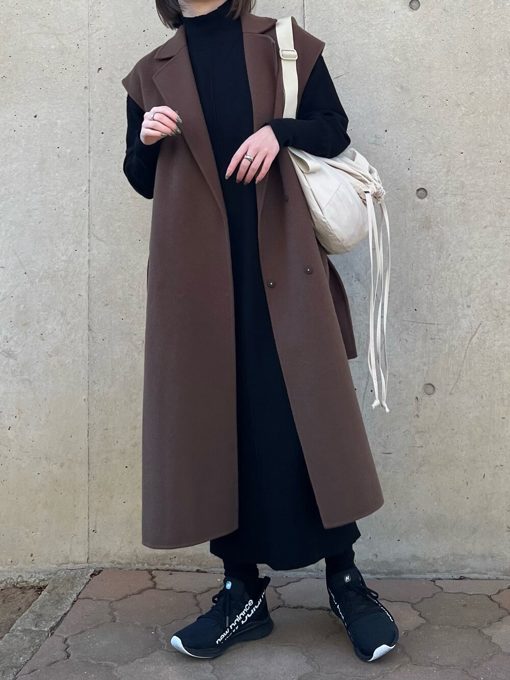 ブラック系のワンピース、ブラウン系のチェスターコート、ホワイト系のバッグを着用したレディースの秋コーディネートの1枚目の写真