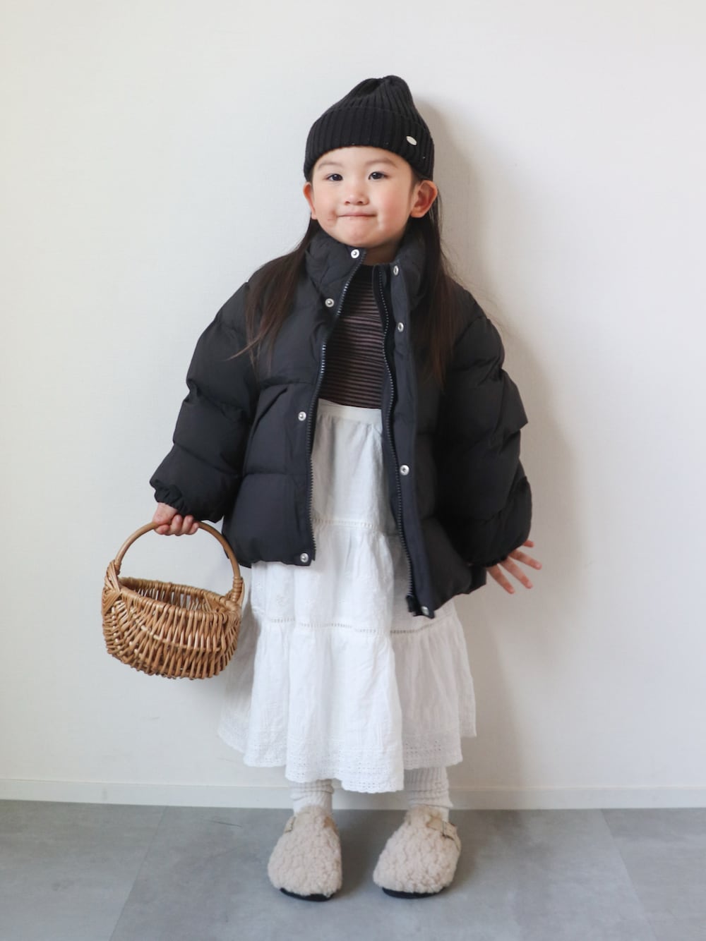 ブラウン系のTシャツ/カットソー、ホワイト系のスカート、ホワイト系のサンダルを着用したキッズの冬コーディネートの1枚目の写真