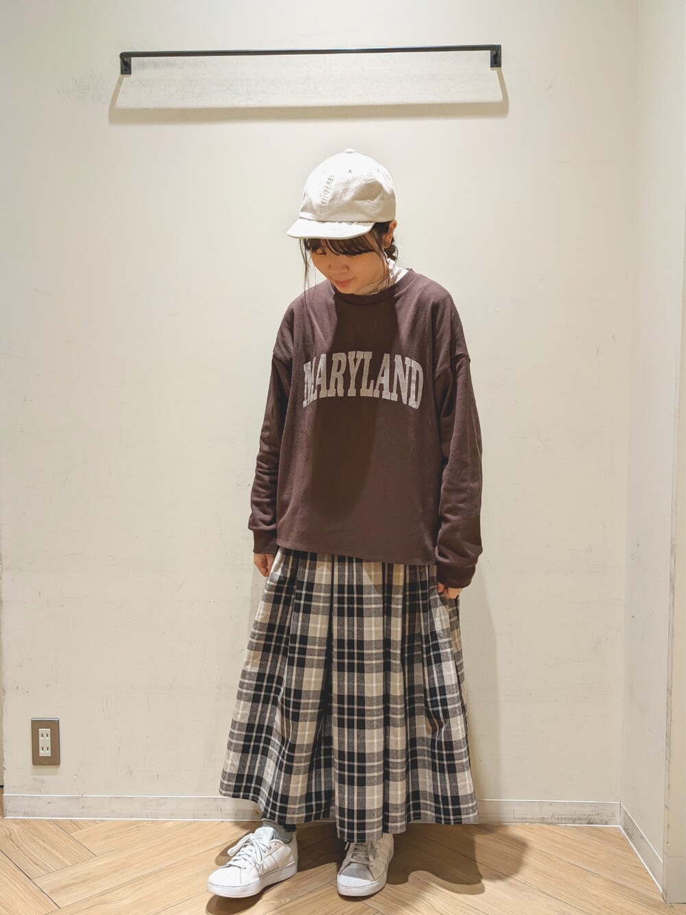 ブラック系のスカート、ブラウン系のTシャツ/カットソー、ベージュ系のニット/セーターを着用したレディースの春コーディネートの1枚目の写真