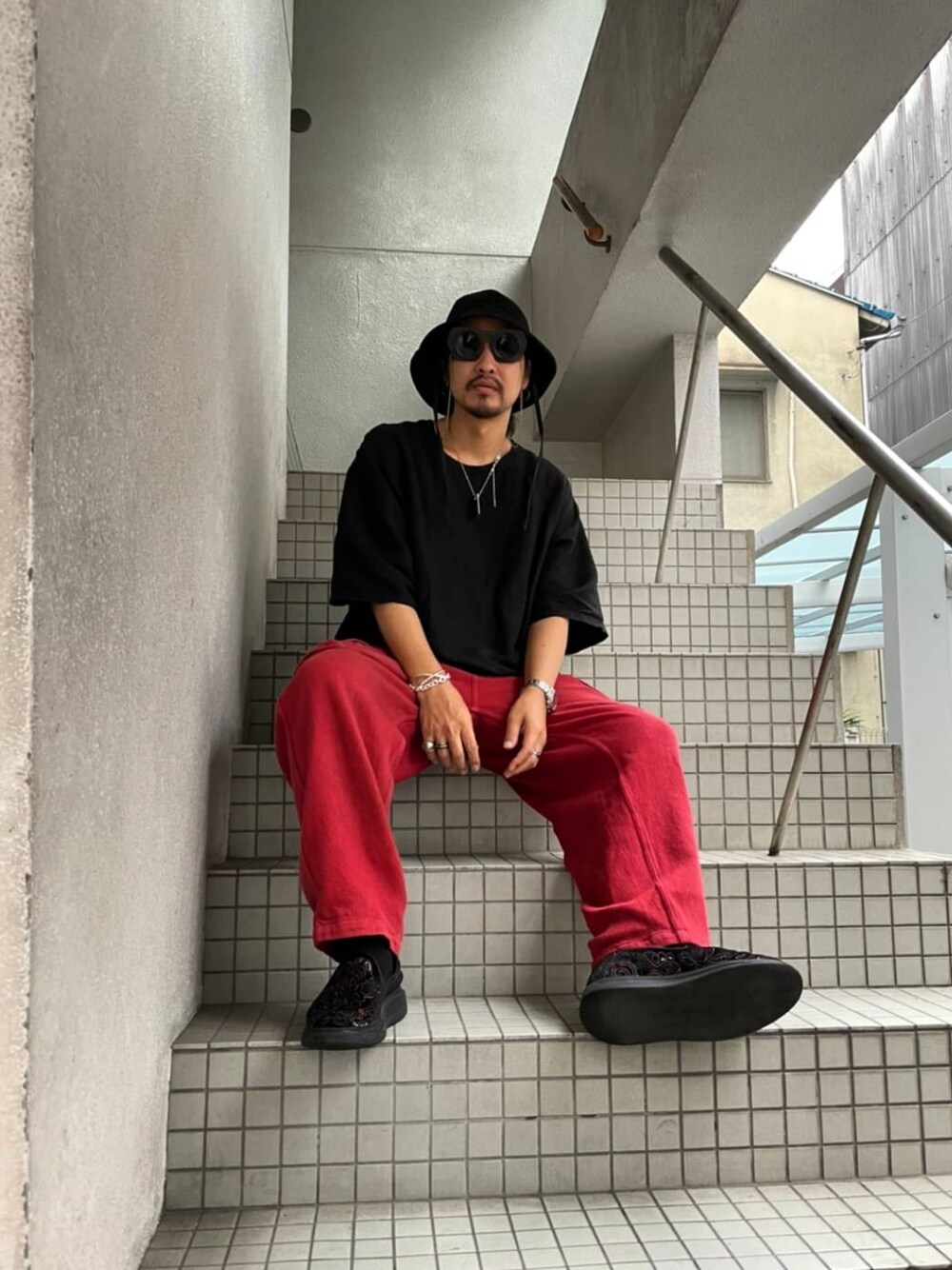 ブラック系のTシャツ/カットソー、レッド系のカーゴパンツ、その他のシューズを着用したメンズの秋コーディネートの1枚目の写真