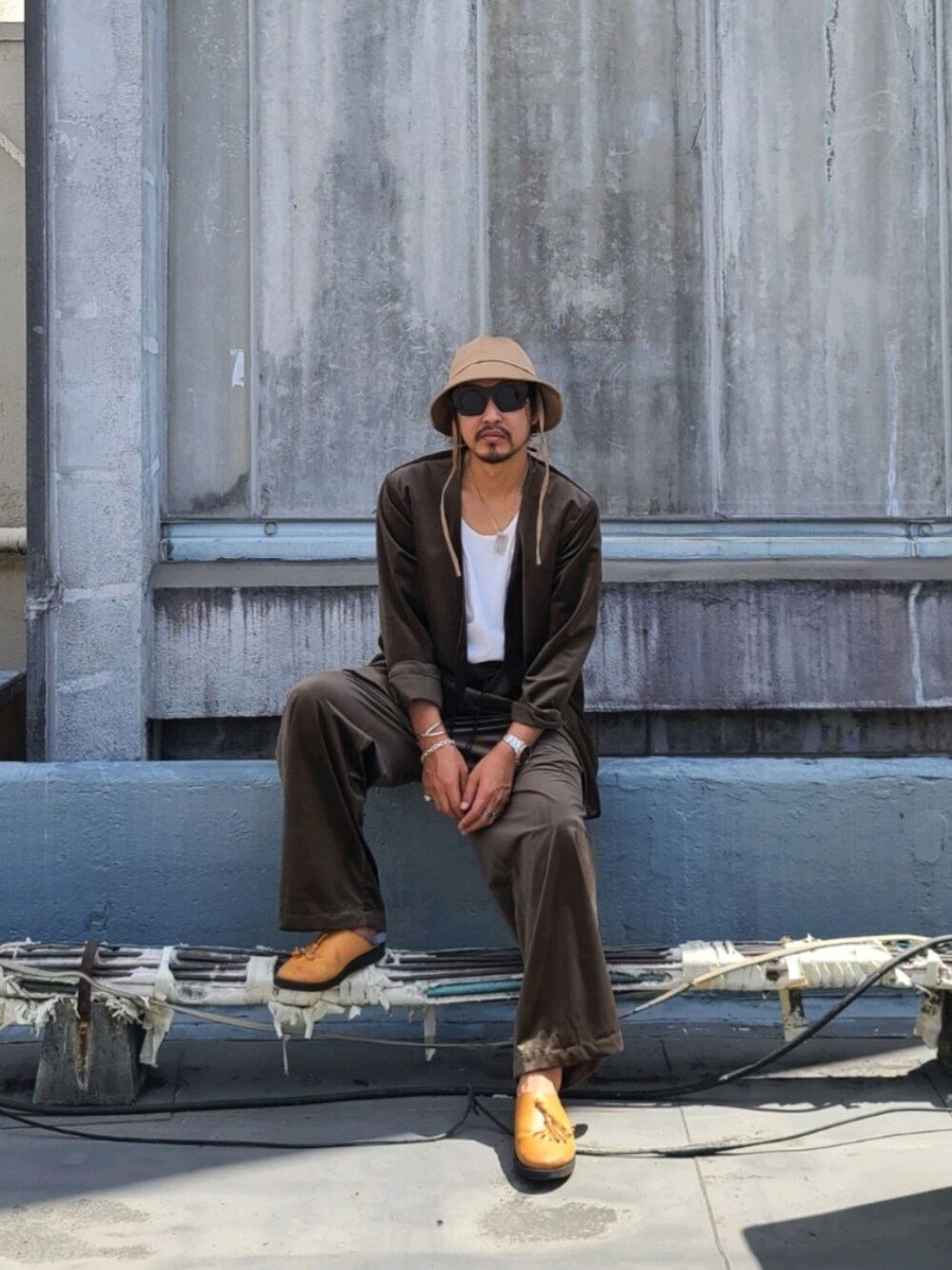 ブラウン系のノーカラージャケット、ホワイト系のトップス、ブラウン系のパンツを着用したメンズの秋コーディネートの1枚目の写真