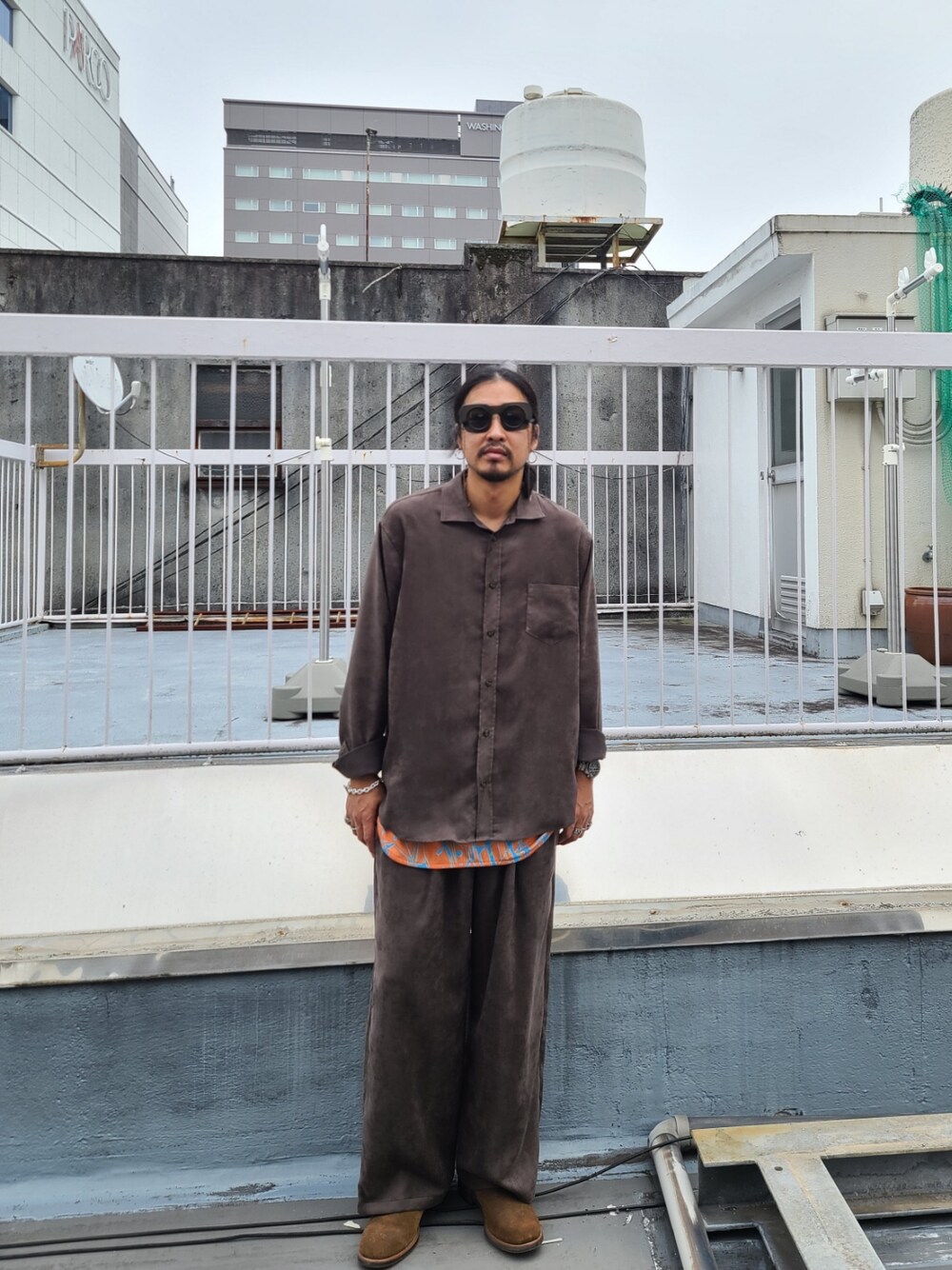 ブラウン系のシャツ/ブラウス、オレンジ系のタンクトップ、ブラウン系のパンツを着用したメンズの秋コーディネートの1枚目の写真