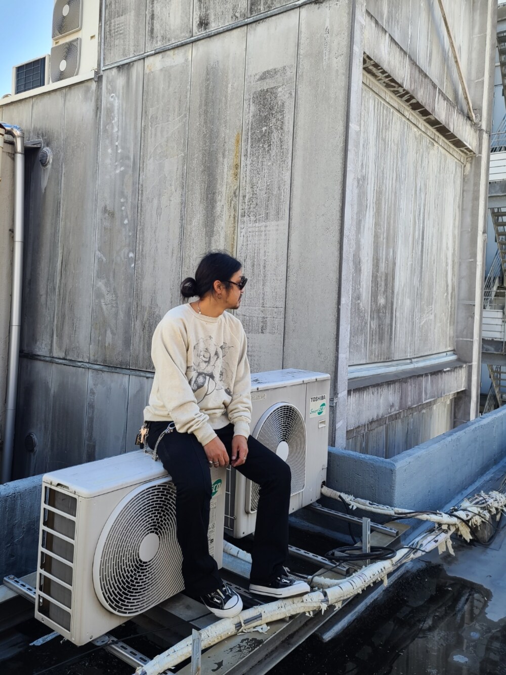 グレー系のスウェット、ブラック系のデニムパンツ、ブラック系のスニーカーを着用したメンズの秋コーディネートの1枚目の写真