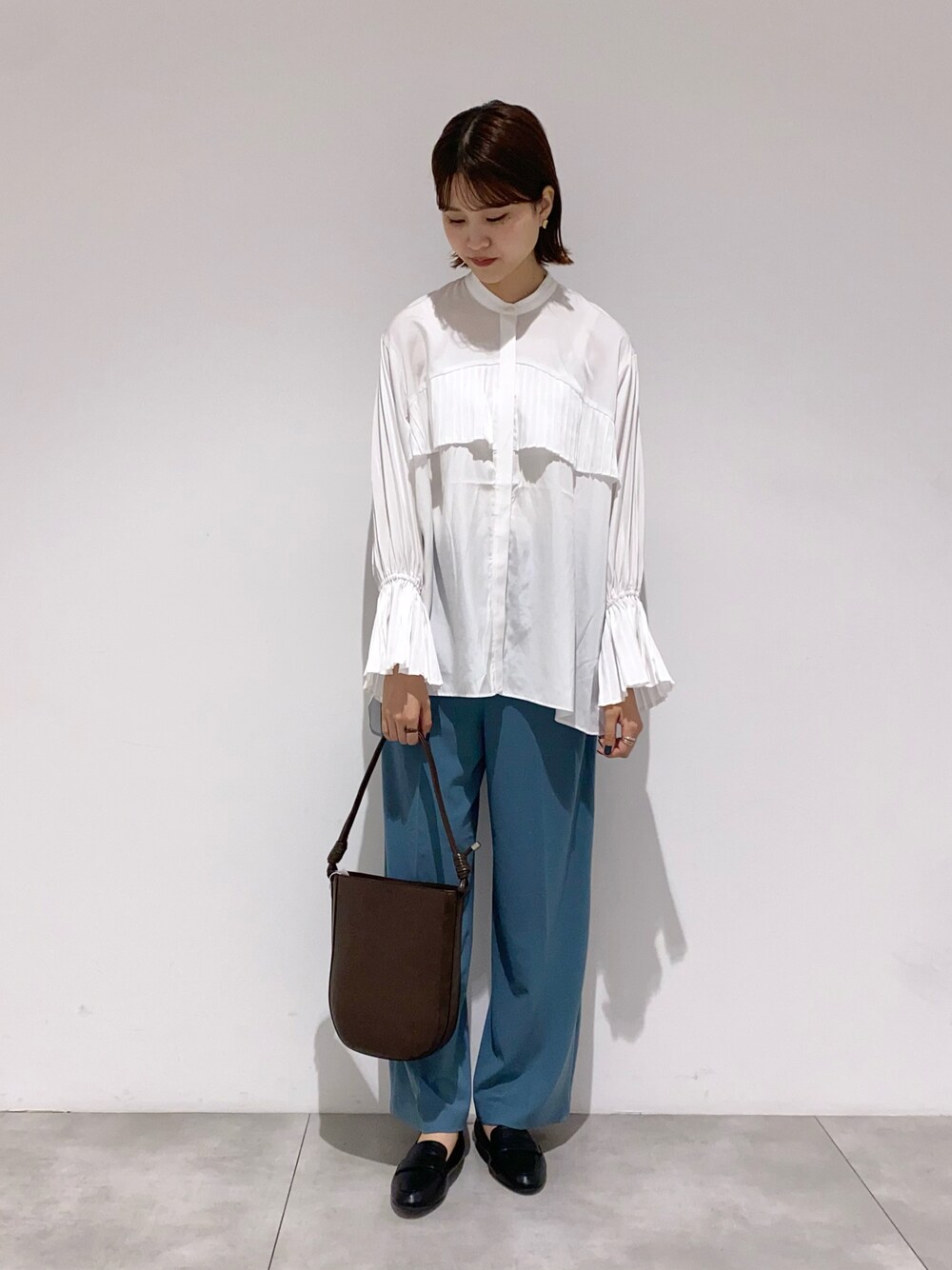 ブラウン系のショルダーバッグ、ブラック系のローファー、ブルー系のその他パンツを着用したレディースの秋コーディネートの1枚目の写真