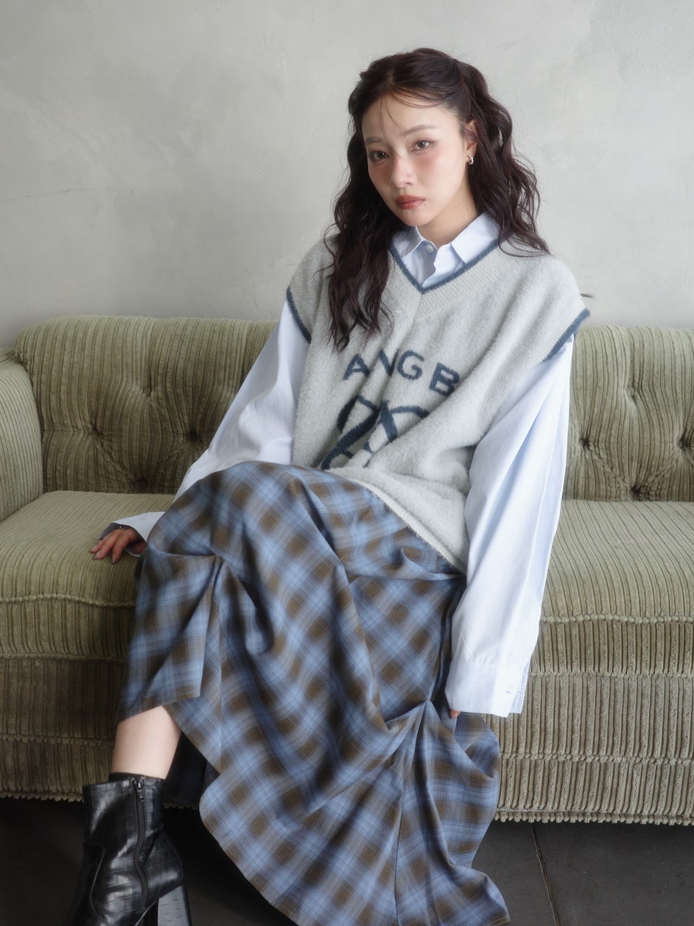 グレー系のベスト、ブルー系のシャツ/ブラウス、ブルー系のスカートを着用したレディースの秋コーディネートの1枚目の写真