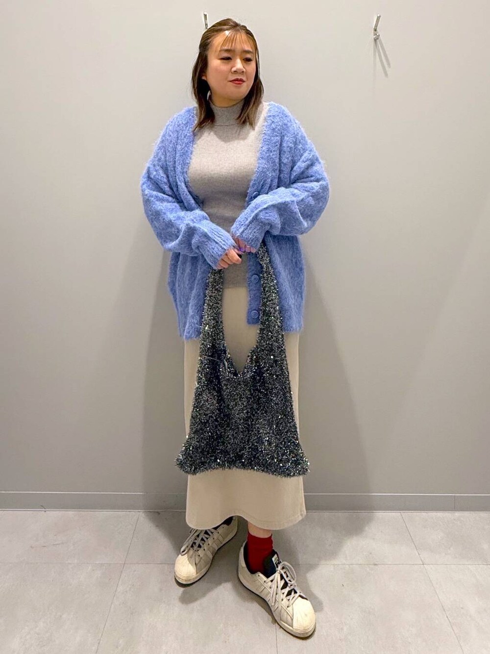 グレー系のニット/セーター、ブルー系のカーディガン/ボレロ、グレー系のトートバッグを着用したレディースの冬コーディネートの1枚目の写真