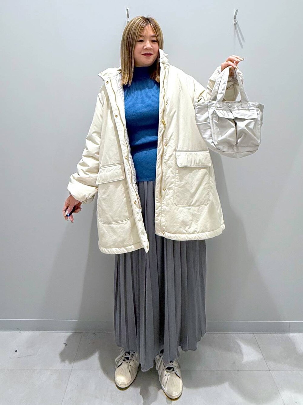 ホワイト系のブルゾン、ブルー系のニット/セーター、グレー系のショルダーバッグを着用したレディースの冬コーディネートの1枚目の写真