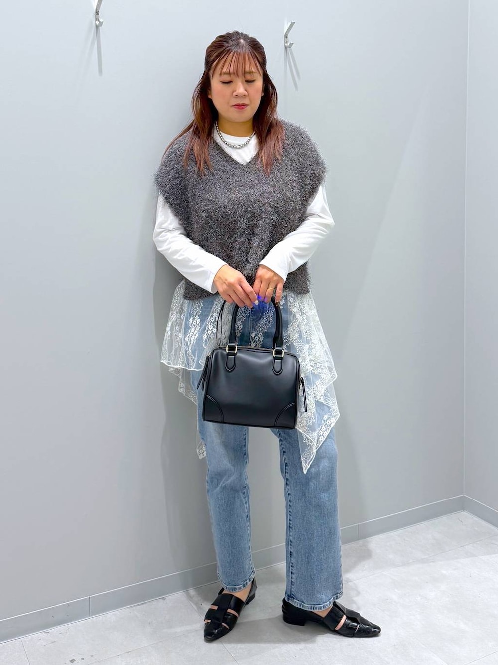 ブラック系のパンプス、ブルー系のデニムパンツ、グレー系のベストを着用したレディースの秋コーディネートの1枚目の写真