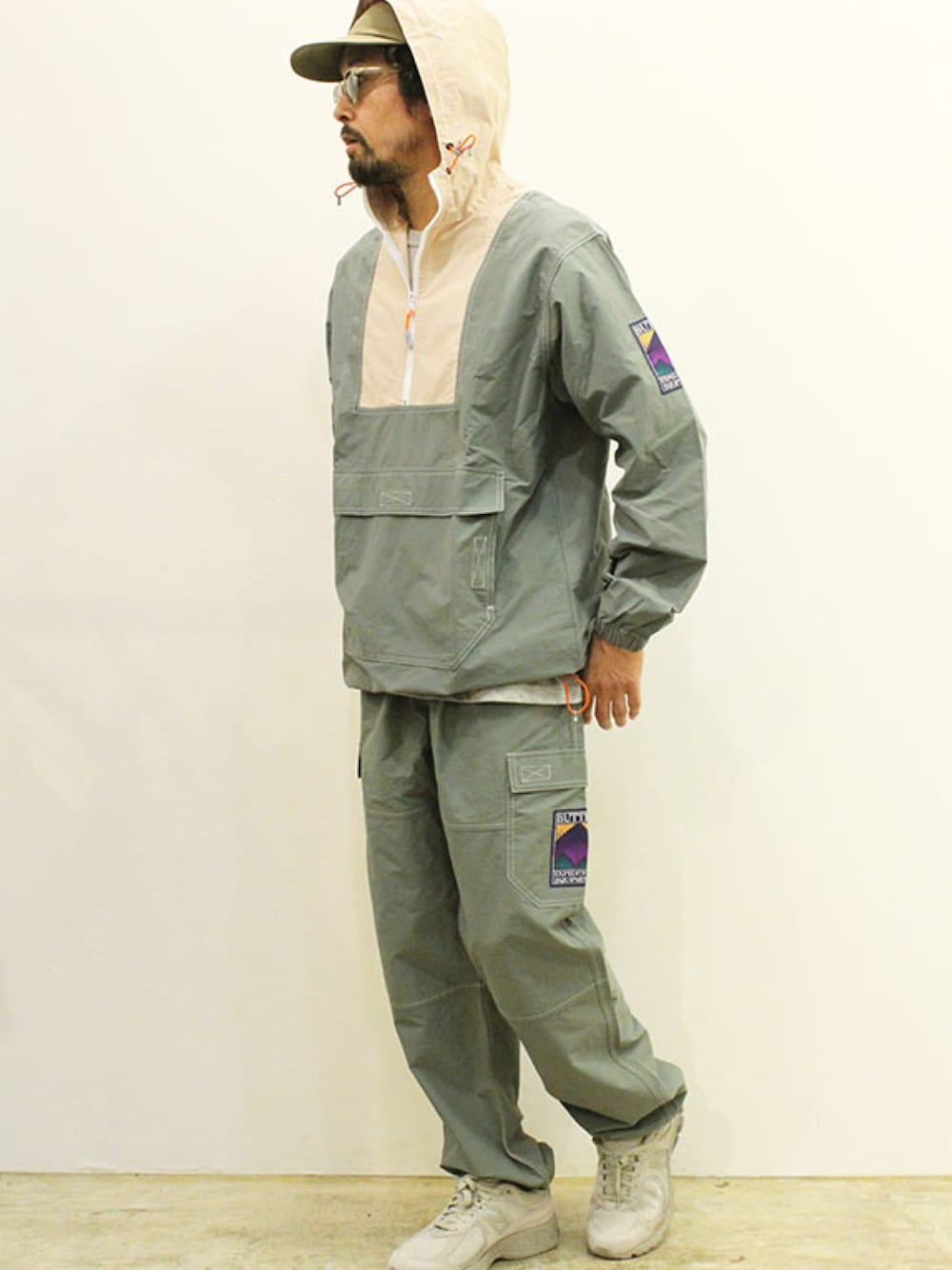 グリーン系のカーゴパンツ、グリーン系のナイロンジャケット、グレー系のスニーカーを着用したメンズの秋コーディネートの1枚目の写真