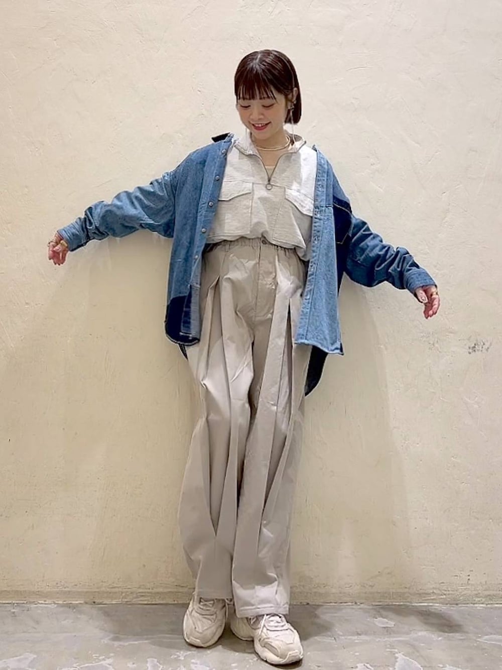 ベージュ系のスウェット、グレー系のチノパンツ、ブルー系のシャツ/ブラウスを着用したレディースの冬コーディネートの1枚目の写真