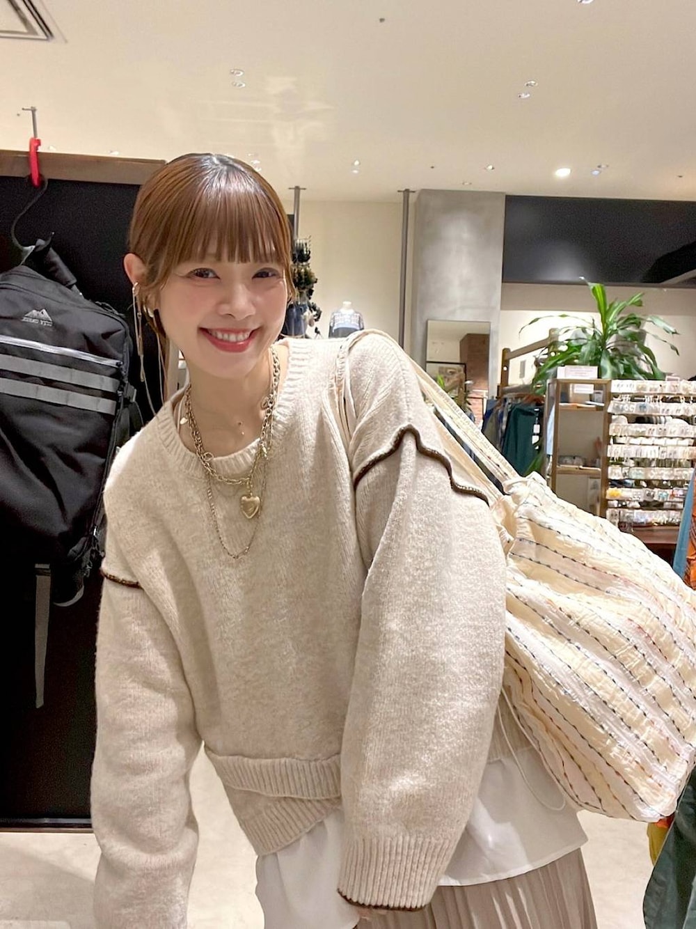 ベージュ系のスカート、その他のトートバッグ、ゴールド系のネックレスを着用したレディースの秋コーディネートの1枚目の写真