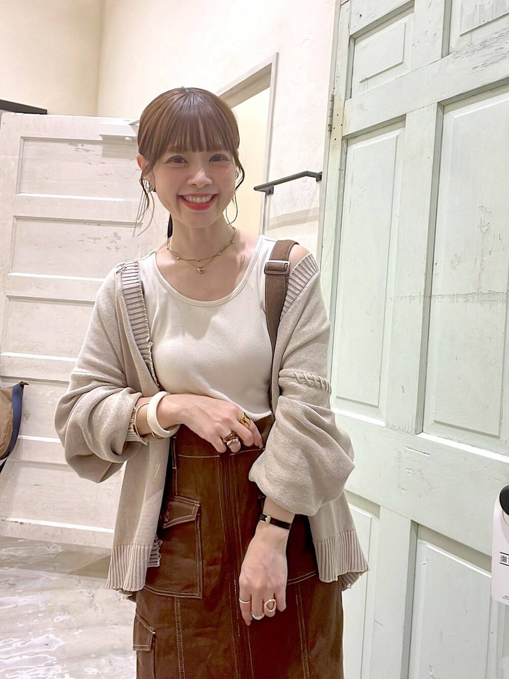 ベージュ系のカーディガン/ボレロ、ブラウン系のスカート、ブラウン系のトートバッグを着用したレディースの秋コーディネートの1枚目の写真