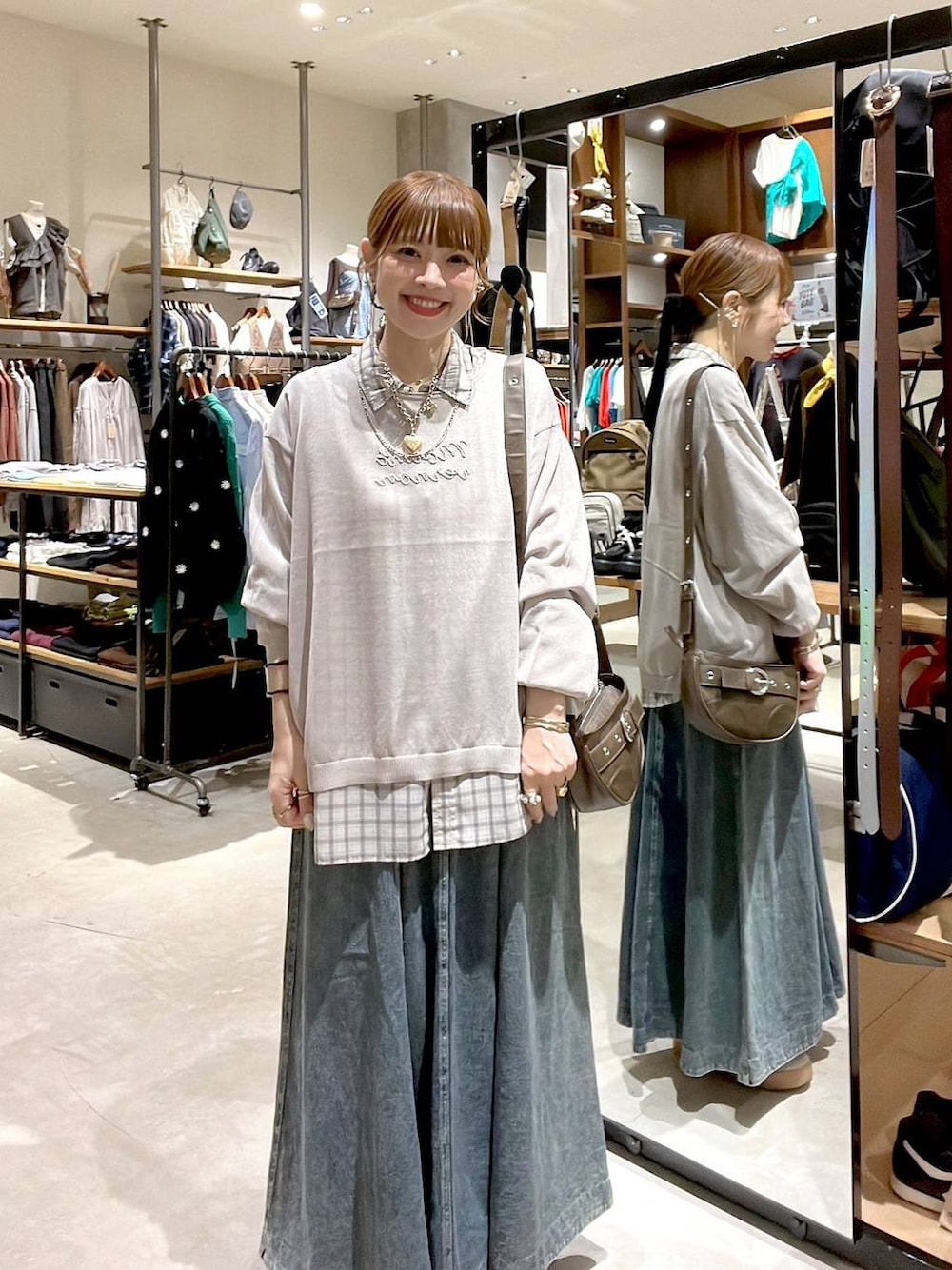 ブルー系のスカート、ホワイト系のシャツ/ブラウス、ブラウン系のショルダーバッグを着用したレディースの秋コーディネートの1枚目の写真