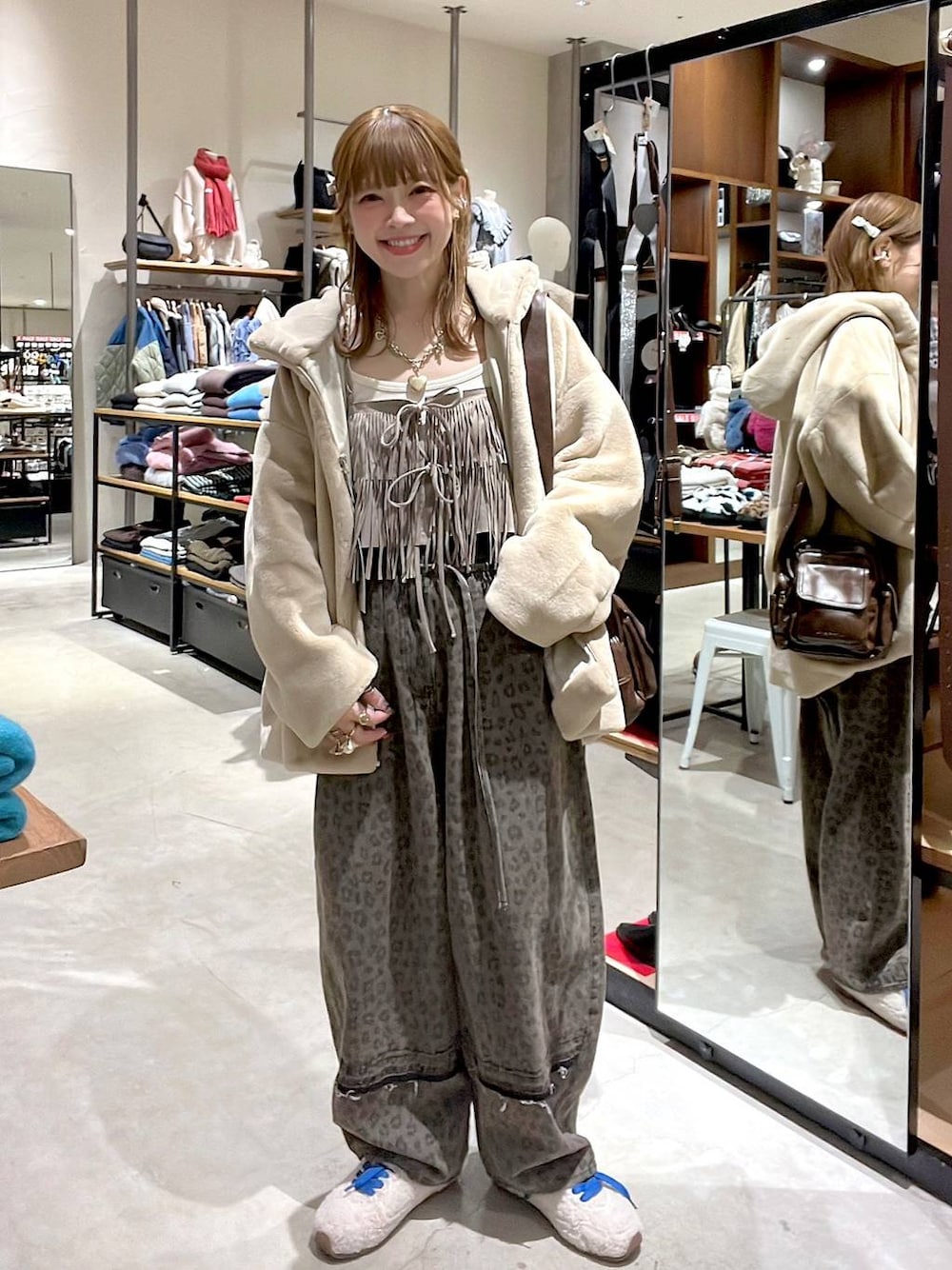 ブラウン系のデニムパンツ、ベージュ系のブルゾン、ブラウン系のショルダーバッグを着用したレディースの冬コーディネートの1枚目の写真