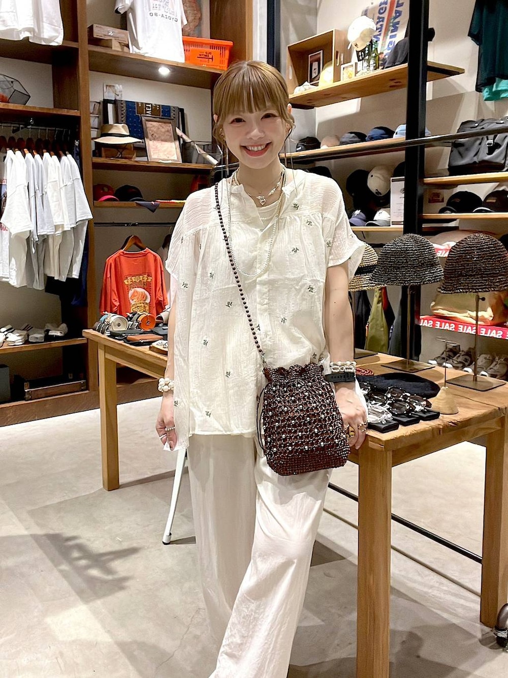 ブラウン系のショルダーバッグ、ホワイト系のシャツ/ブラウスを着用したレディースの夏コーディネートの1枚目の写真
