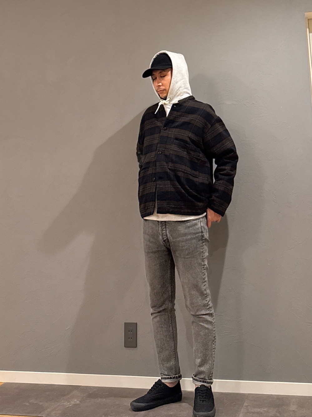 グレー系のパーカー、グレー系のデニムパンツ、ブラック系のスニーカーを着用したメンズの秋コーディネートの1枚目の写真