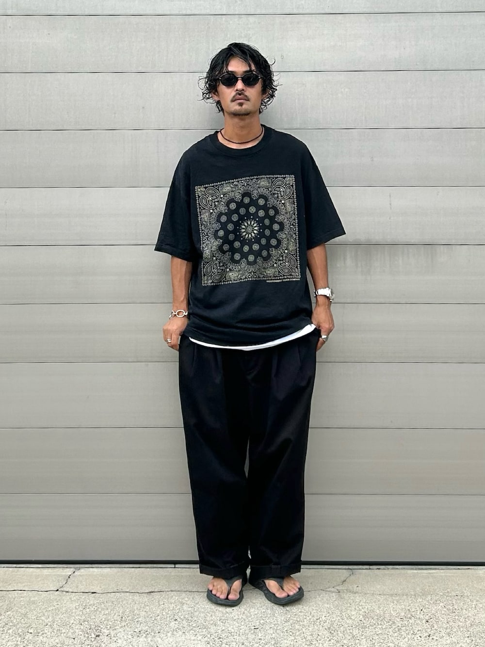 「オーバーサイズ、プリントT、スラックス、サンダル、サングラス、古着、古着MIX、ストリート、休日スタイル、ブラックコーデ、ブラック、シンプルスタイル、ラフコーデ」｜「HOKAのHOKA ONEONE ORA RECOVERY FLIP (Black/Dark Gull Gray)（サンダル、ブラック系）」を使った、takuya.sさん（メンズ・171cm）の秋コーディネートの1枚目の写真