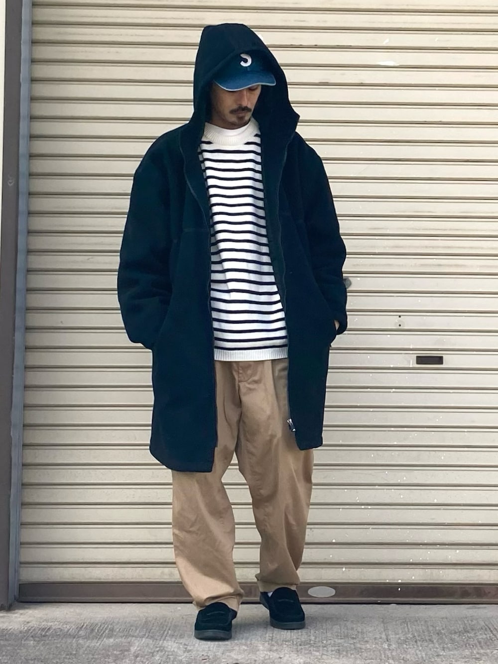 ベージュ系のニット/セーター、ベージュ系のチノパンツ、ブラック系のローファーを着用したメンズの冬コーディネートの1枚目の写真