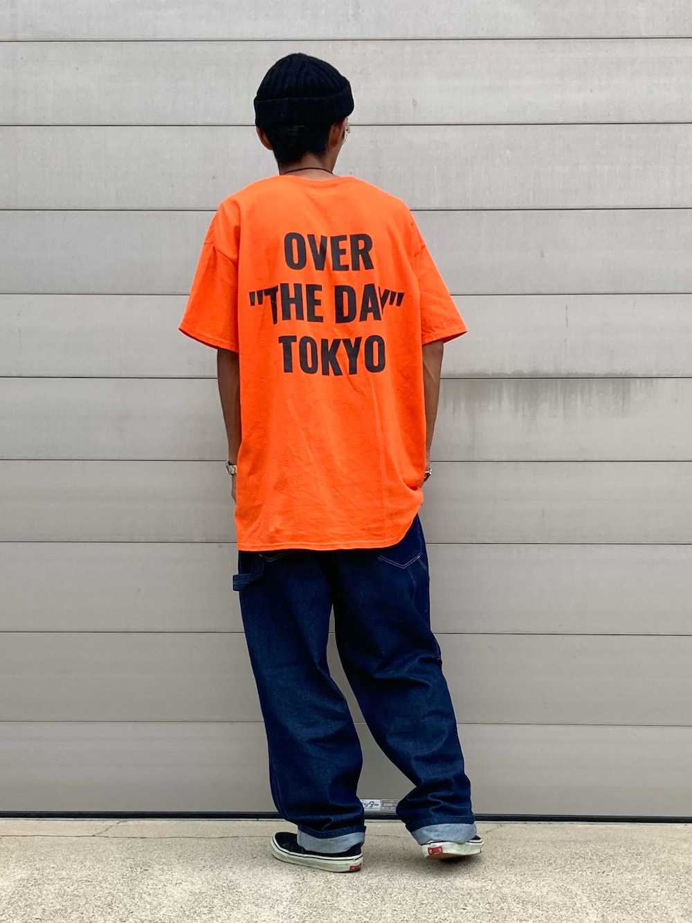 ブルー系のデニムパンツ、オレンジ系のTシャツ/カットソー、ブラック系のスニーカーを着用したメンズの秋コーディネートの1枚目の写真