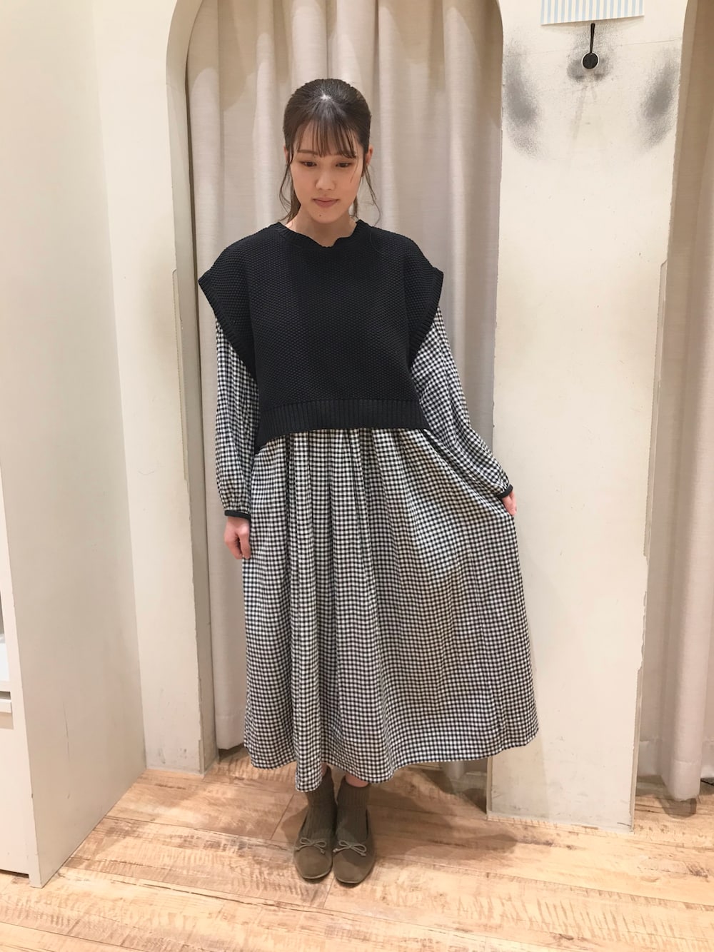 ブラック系のワンピース、ブラック系のベスト、ベージュ系のバレエシューズを着用したレディースの冬コーディネートの1枚目の写真