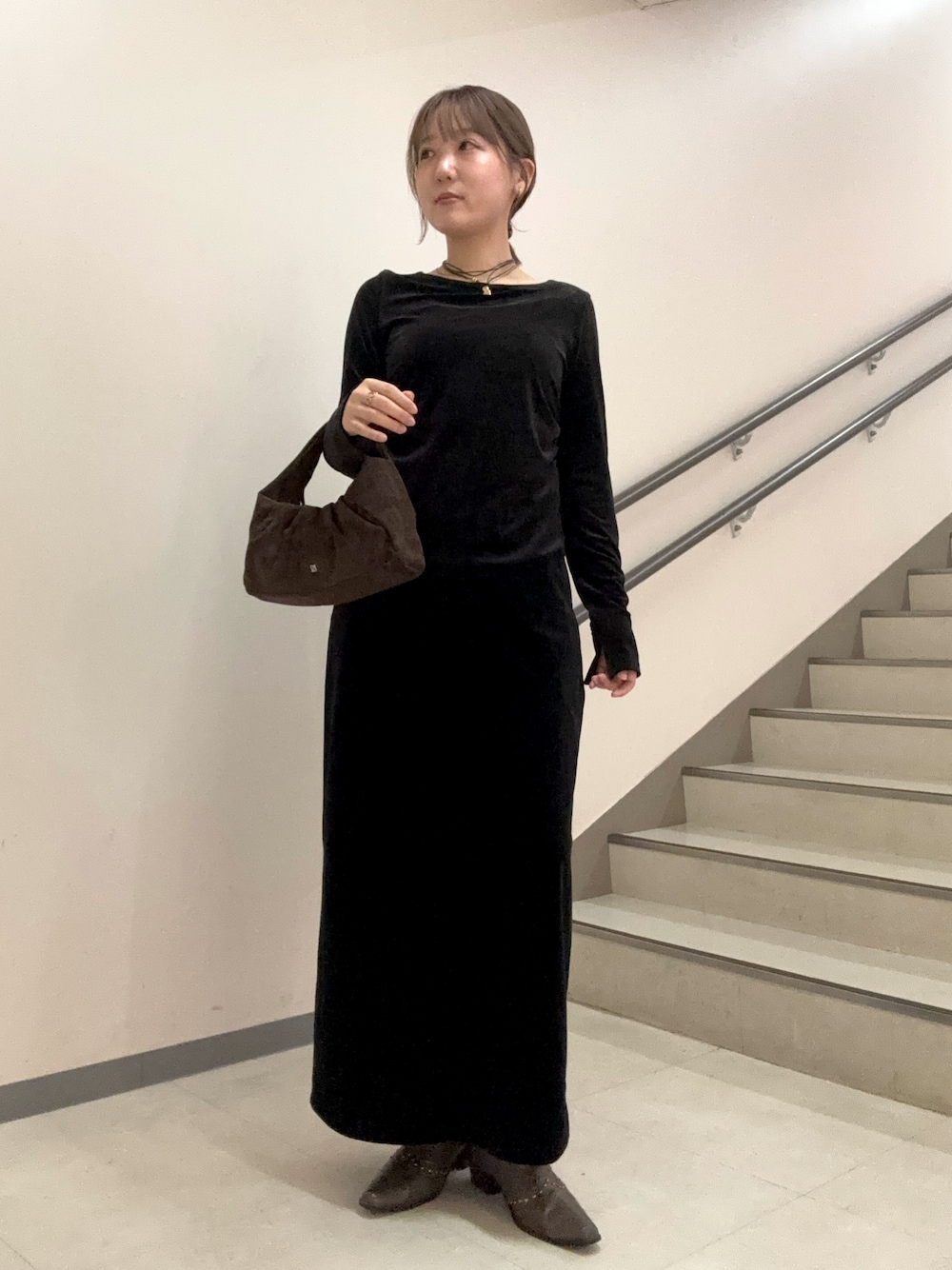 ブラック系のスカート、ブラック系のTシャツ/カットソー、ブラウン系のハンドバッグを着用したレディースの秋コーディネートの1枚目の写真
