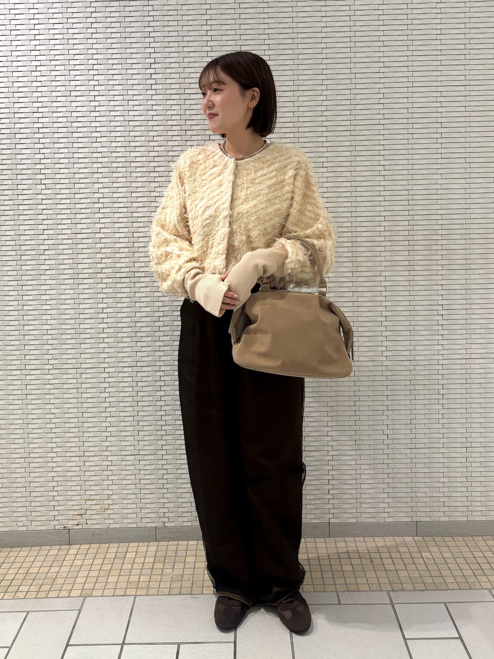 ベージュ系のボストンバッグ、ブラウン系のその他パンツ、ブラウン系のスニーカーを着用したレディースの冬コーディネートの1枚目の写真