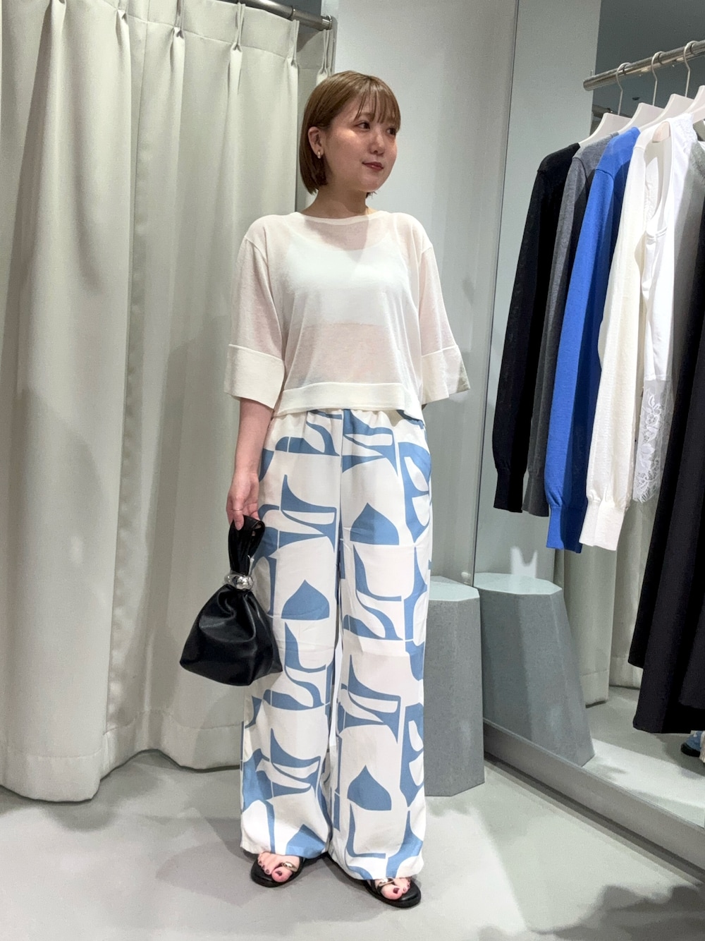 ブルー系のその他パンツ、ブラック系のハンドバッグ、ホワイト系のニット/セーターを着用したレディースの夏コーディネートの1枚目の写真