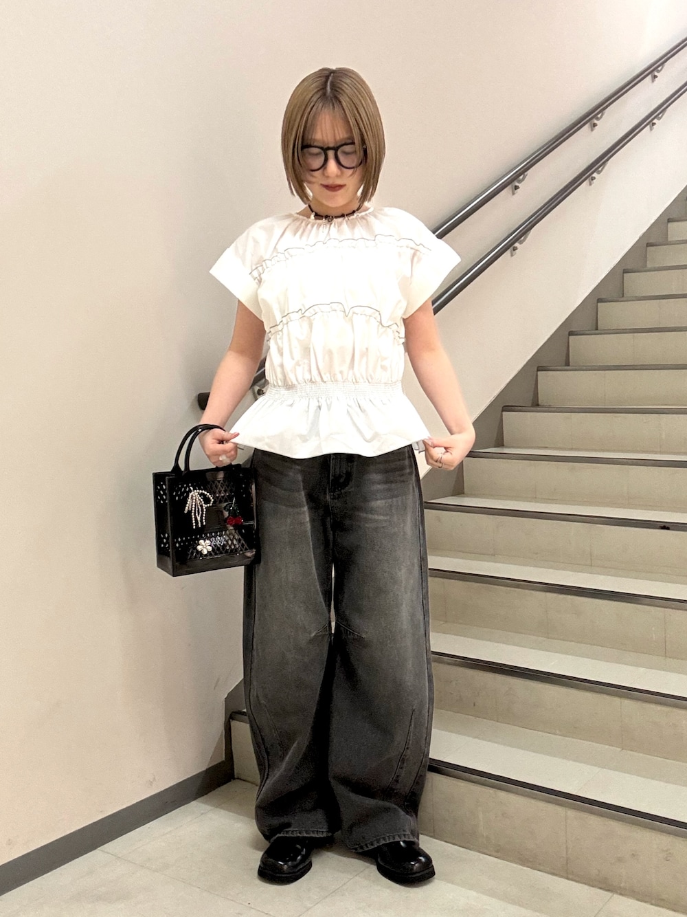 グレー系のデニムパンツ、ホワイト系のシャツ/ブラウス、ブラック系のハンドバッグを着用したレディースの春コーディネートの1枚目の写真