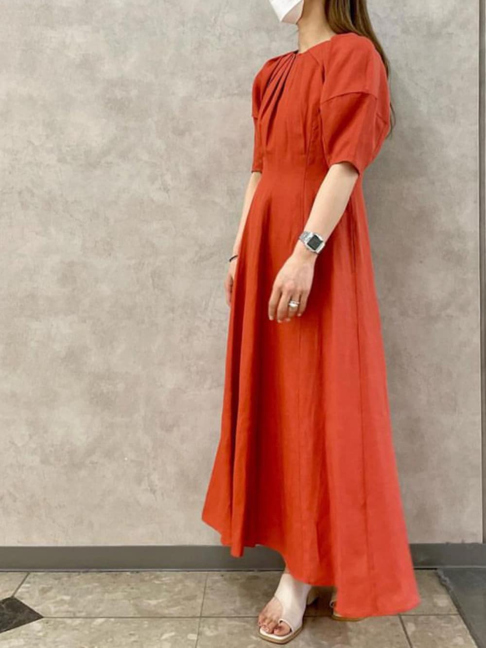 オレンジ系のワンピース、ブラック系のサンダルを着用したレディースの春コーディネートの1枚目の写真