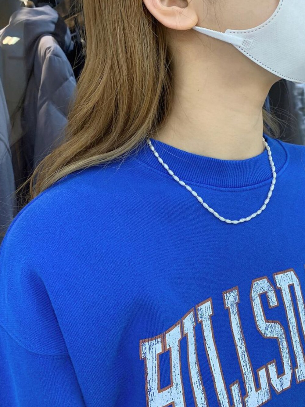 ブルー系のスウェット、ホワイト系のネックレスを着用したレディースの冬コーディネートの1枚目の写真