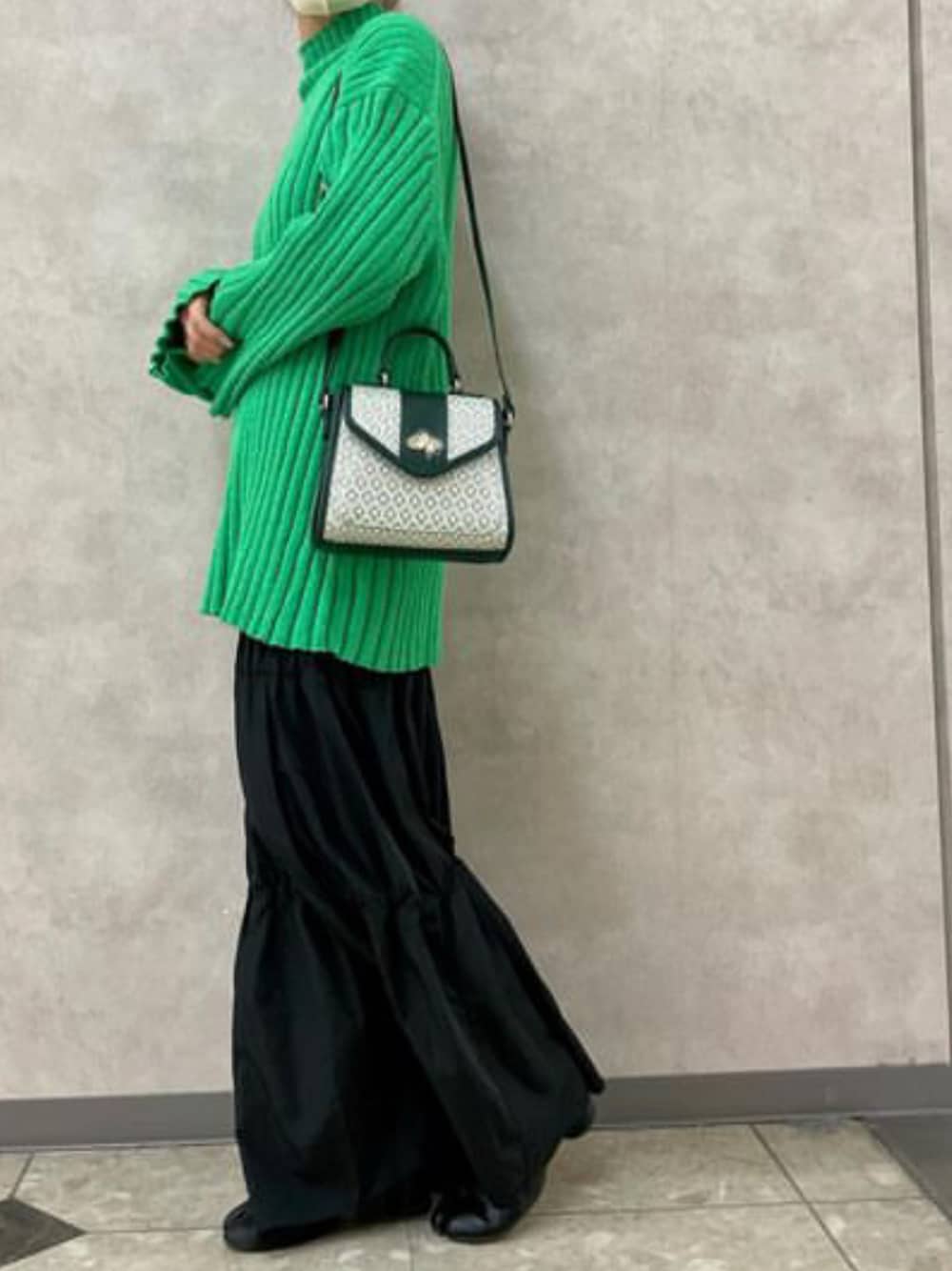 グリーン系のショルダーバッグ、ブラック系のスカート、グリーン系のニット/セーターを着用したレディースの冬コーディネートの1枚目の写真