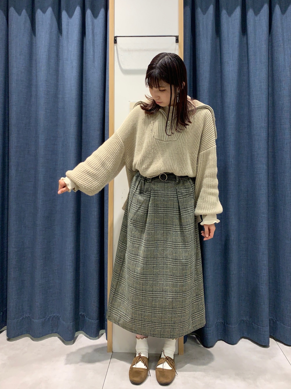 グレー系のスカート、ホワイト系のニット/セーター、ベージュ系のニット/セーターを着用したレディースの秋コーディネートの1枚目の写真